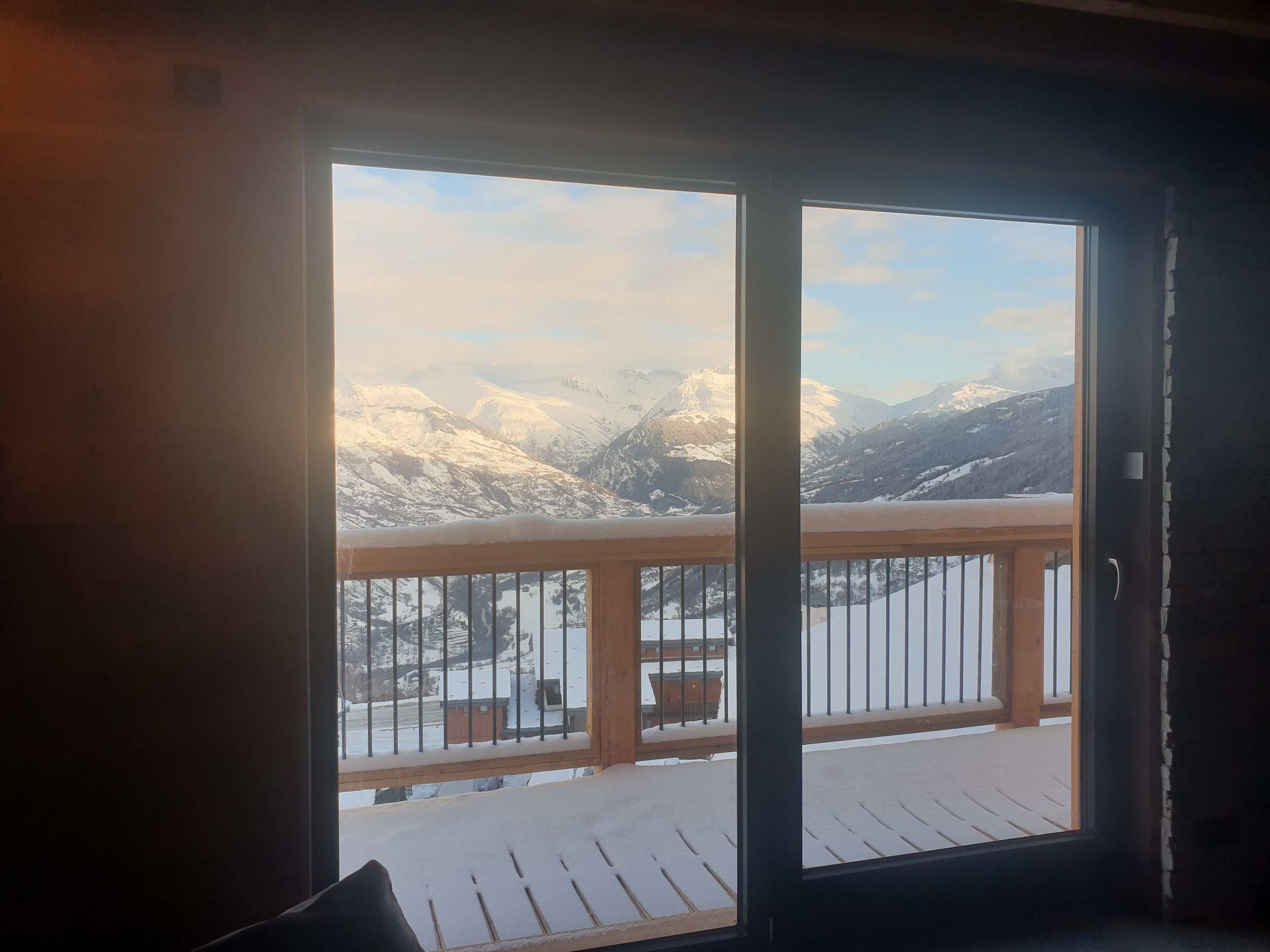 A room with a large window overlooking a snowy mountain landscape.