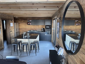 A modern kitchen with a central island, bar stools, and a large mirror. - SKI IN SKI OUT PARADISKI LA PLAGNE LES COCHES TOP OF THE RANGE CHALET (Bellentre)