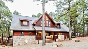 Une cabane en rondins avec des fondations en pierre, un toit en métal et une terrasse en bois.