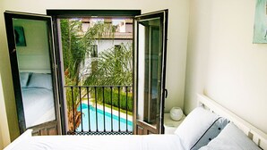 Un dormitorio con cama, mesita de noche y vistas a una piscina a través de una puerta abierta.