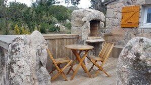 A rustic outdoor seating area with a stone wall, wooden table, and chairs. - Santa-Giulia beach&Bergerie&U Caseddu (Porto-Vecchio)