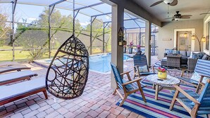 A covered patio with a pool, outdoor seating, and ceiling fans.