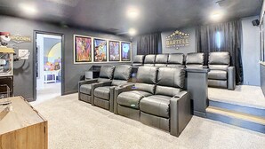 A home theater with leather recliners, a popcorn machine, and framed movie posters on the wall.