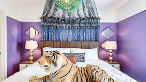 A bedroom with a bed, a tiger plush toy, a canopy, and two nightstands with lamps.