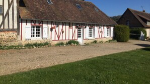 A traditional half-timbered building with a gravel driveway and a well-maintained lawn.