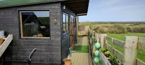 Una cabaña de madera con un ventanal grande, una terraza y vistas al campo.