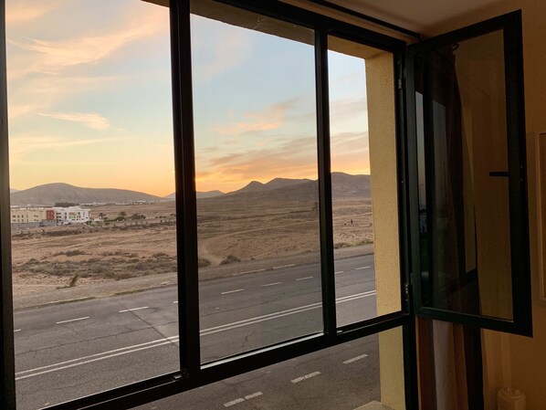 Ein Zimmer mit einem großen Fenster mit Blick auf eine Wüstenlandschaft mit Bergen und einer Straße.