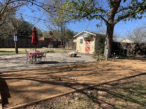 A backyard with a patio table, a small shed, and a fenced yard. - " BLUE SKYLARK" is two blocks from main and one mile from Historic downtown. (Fredericksburg)
