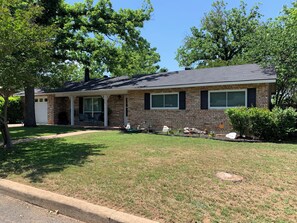 A single-story brick house with a front porch, a garage, and a well-maintained lawn. - " BLUE SKYLARK" is two blocks from main and one mile from Historic downtown. (Fredericksburg)