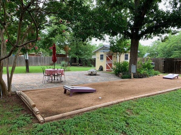 A backyard with a sandbox, a patio table, and a covered seating area. - " BLUE SKYLARK" is two blocks from main and one mile from Historic downtown. (Fredericksburg)
