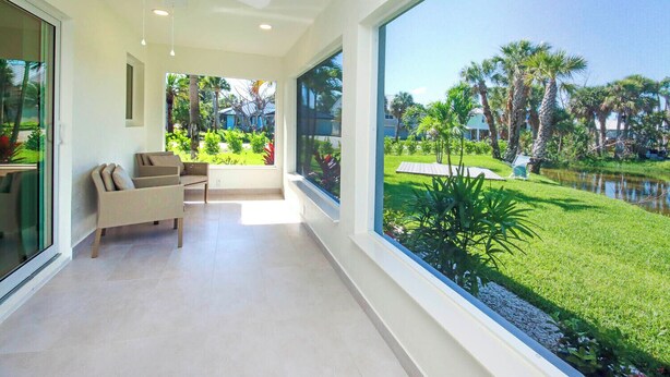 A modern room with a large window, a ceiling fan, and a view of a well-maintained garden with a pond.