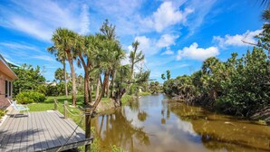 A wooden deck with chairs, a river, and surrounding greenery.