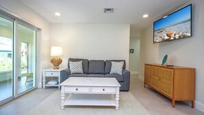 A modern living room with a grey sofa, white coffee table, and wooden cabinet.