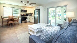 A modern kitchen with white cabinets, a stainless steel refrigerator, and a dining area with a wooden table and chairs.