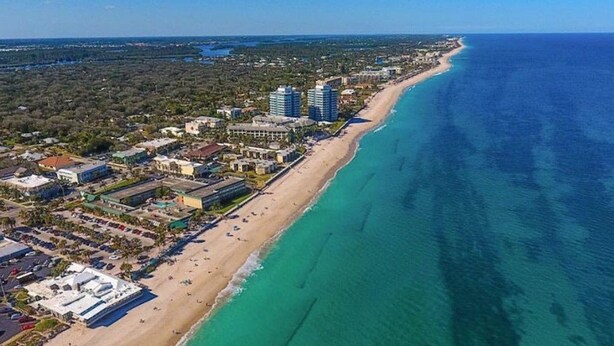 An aerial view of a coastal area with a beach, buildings, and a clear blue ocean. - Central Beach 2 BR under the oaks on Cardinal Drive; 2 min, walk to beach (Vero Beach)