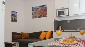 A modern living room with a sofa, a glass coffee table, and a kitchen area with a microwave.