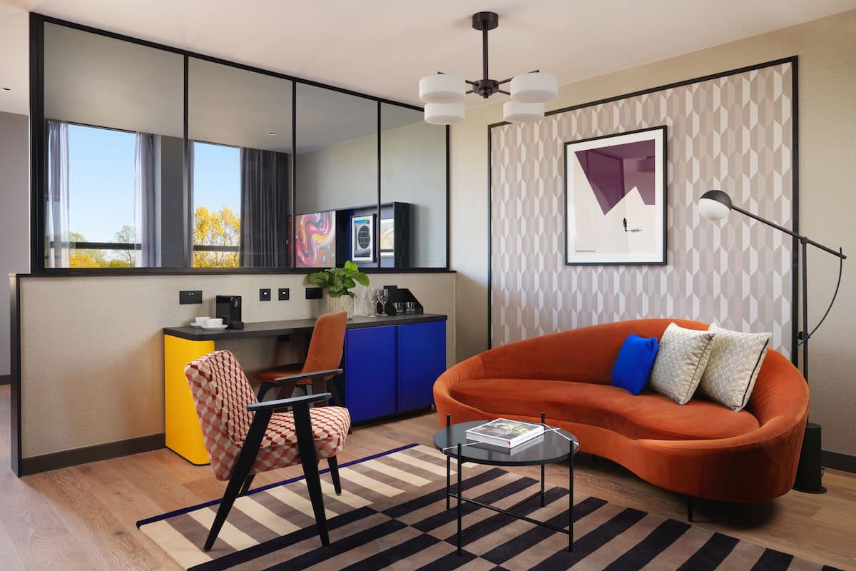 Una sala de estar moderna con un sofá, una silla, una mesa de centro y un comedor con una barra y armarios.
