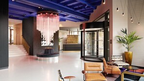 A modern lobby with a staircase, seating areas, a reception desk, and a large chandelier. - Malmaison York (York)