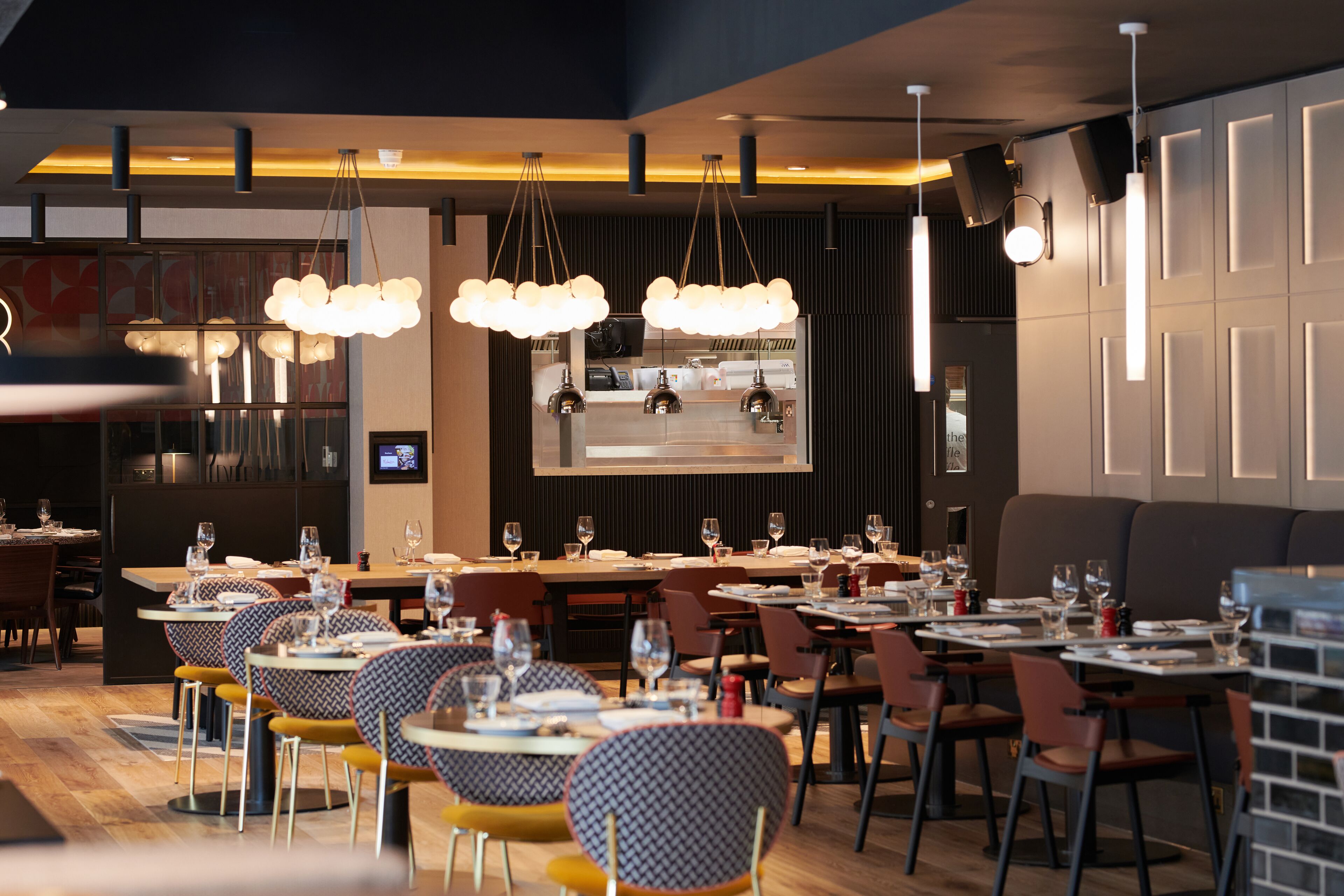 A restaurant with multiple dining tables and chairs, a bar area, and a modern interior design.