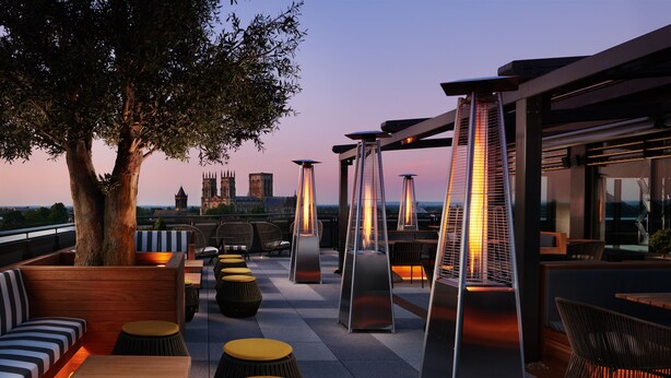 An outdoor seating area with modern furniture and a view of a historic building in the background. - Malmaison York (York)