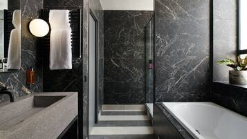 A modern bathroom with a marble backsplash, a large bathtub, and a vanity with a sink.