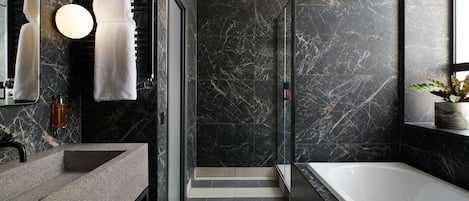 A modern bathroom with a marble backsplash, a large bathtub, and a vanity with a sink.