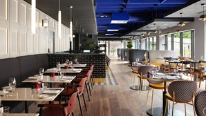 A modern restaurant with high ceilings, exposed beams, and a mix of seating styles including booths and tables. - Malmaison York (York)