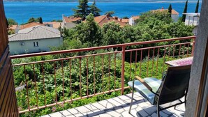 Ein Balkon mit Blick auf das Meer, umgeben von Grünflächen und Gebäuden.