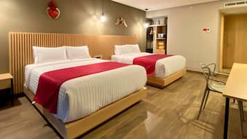 Hotellihuone, jossa on kaksi sänkyä, puinen pääty ja pieni pöytä sekä tuoli.