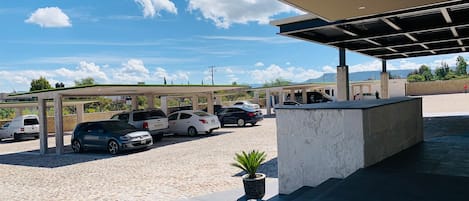 Un aparcamiento con plazas de coches cubiertas y un jardín central.