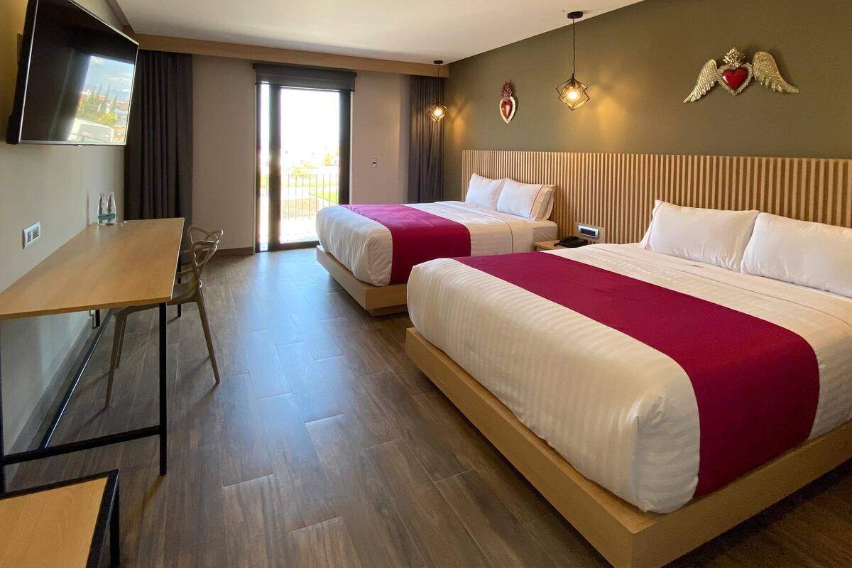 Une chambre d’hôtel avec deux lits, un bureau et une télévision.