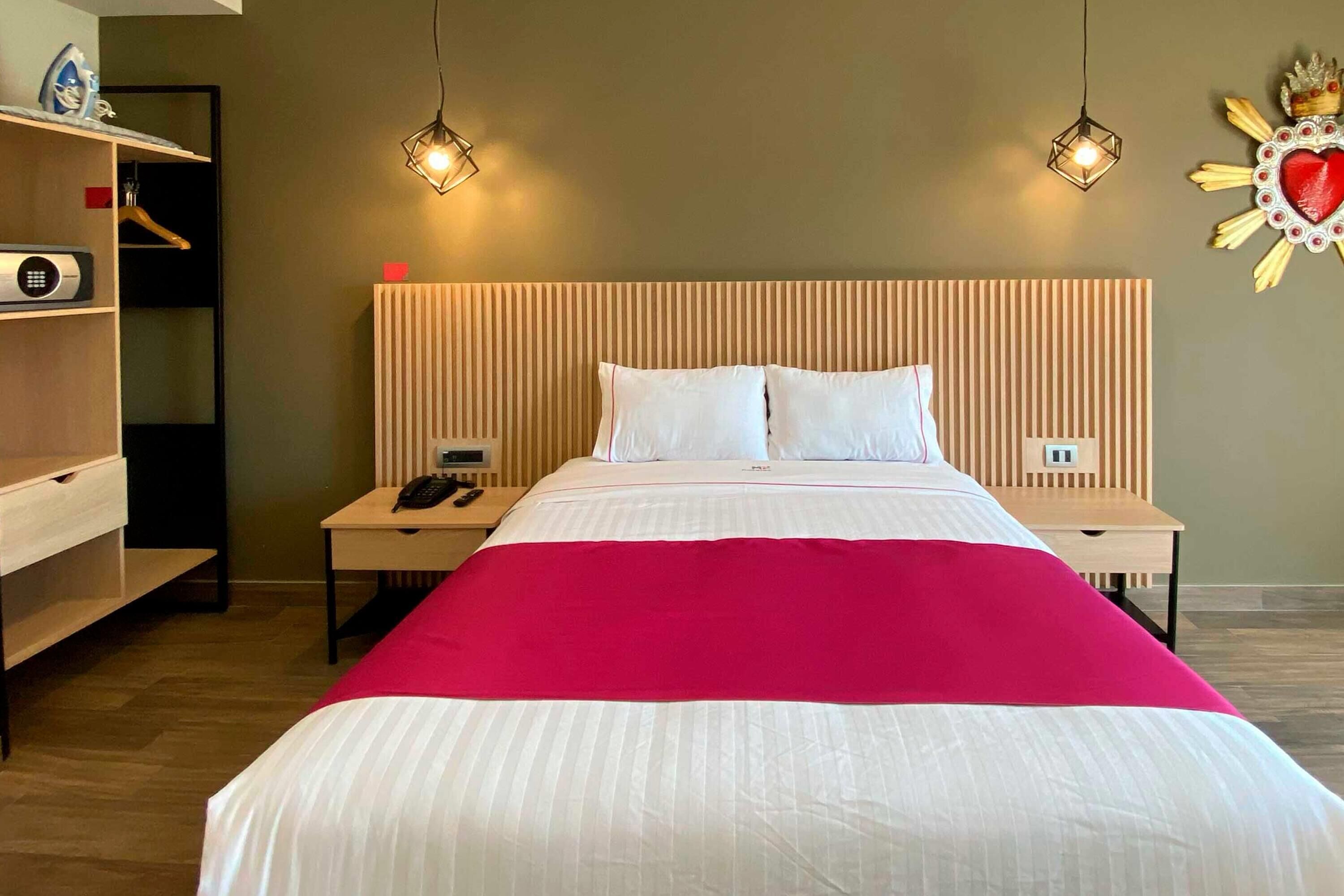 Een hotelkamer met een groot bed, twee nachtkastjes, een kledingkast en een decoratief wandobject.