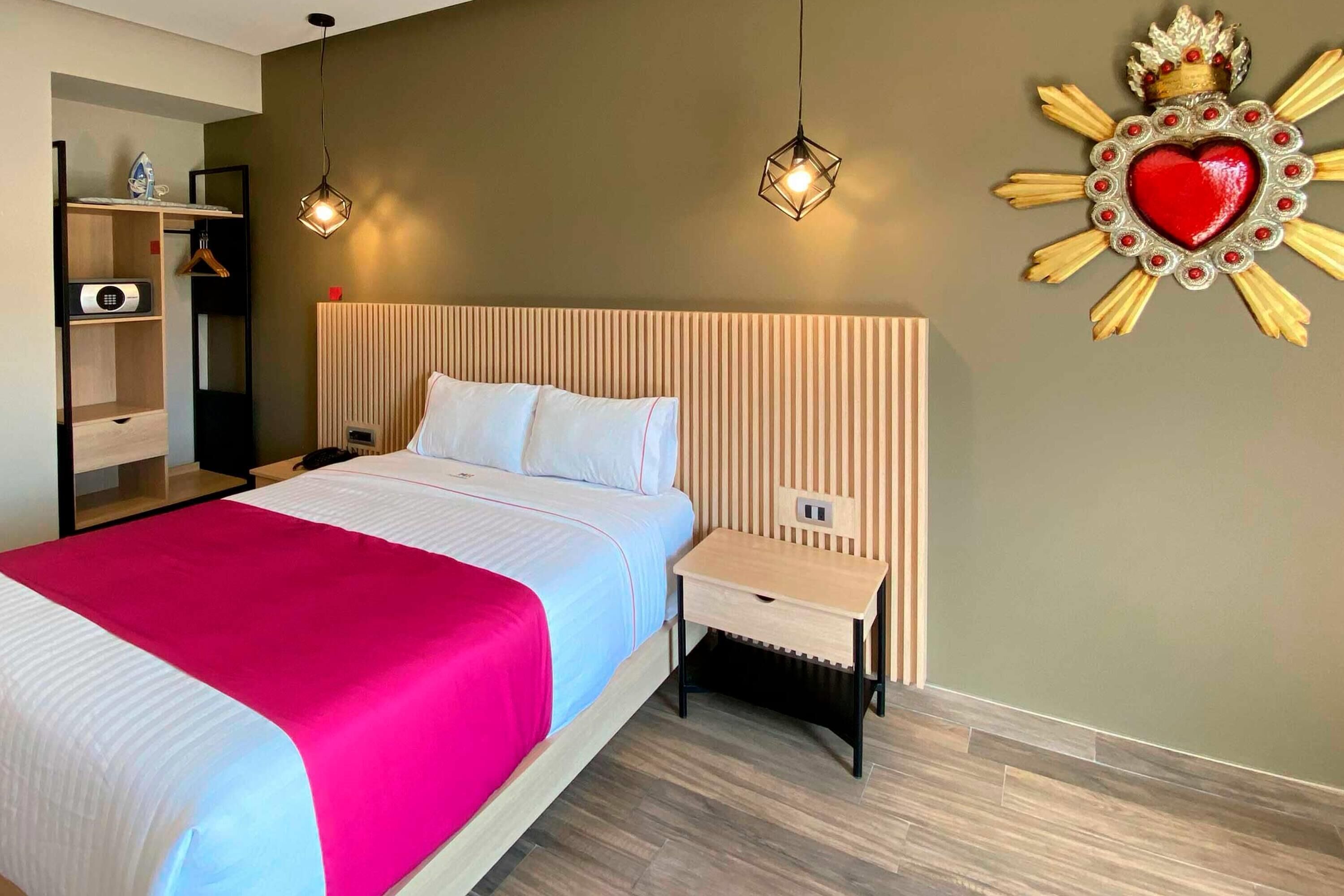 A hotel room with a bed, bedside table, and a wall decoration.