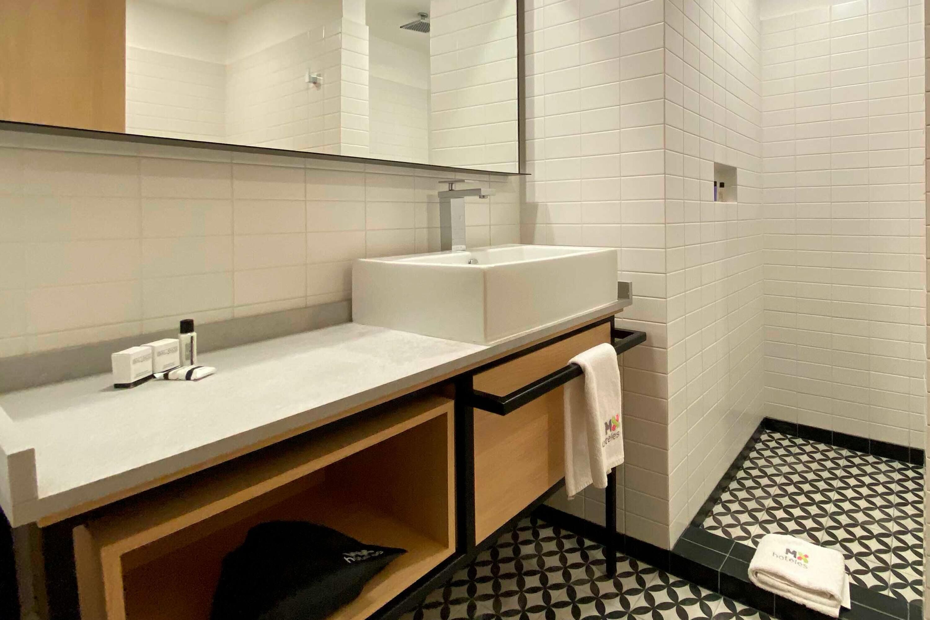 Un bagno moderno con lavandino bianco, specchio e pavimento a motivi bianchi e neri.