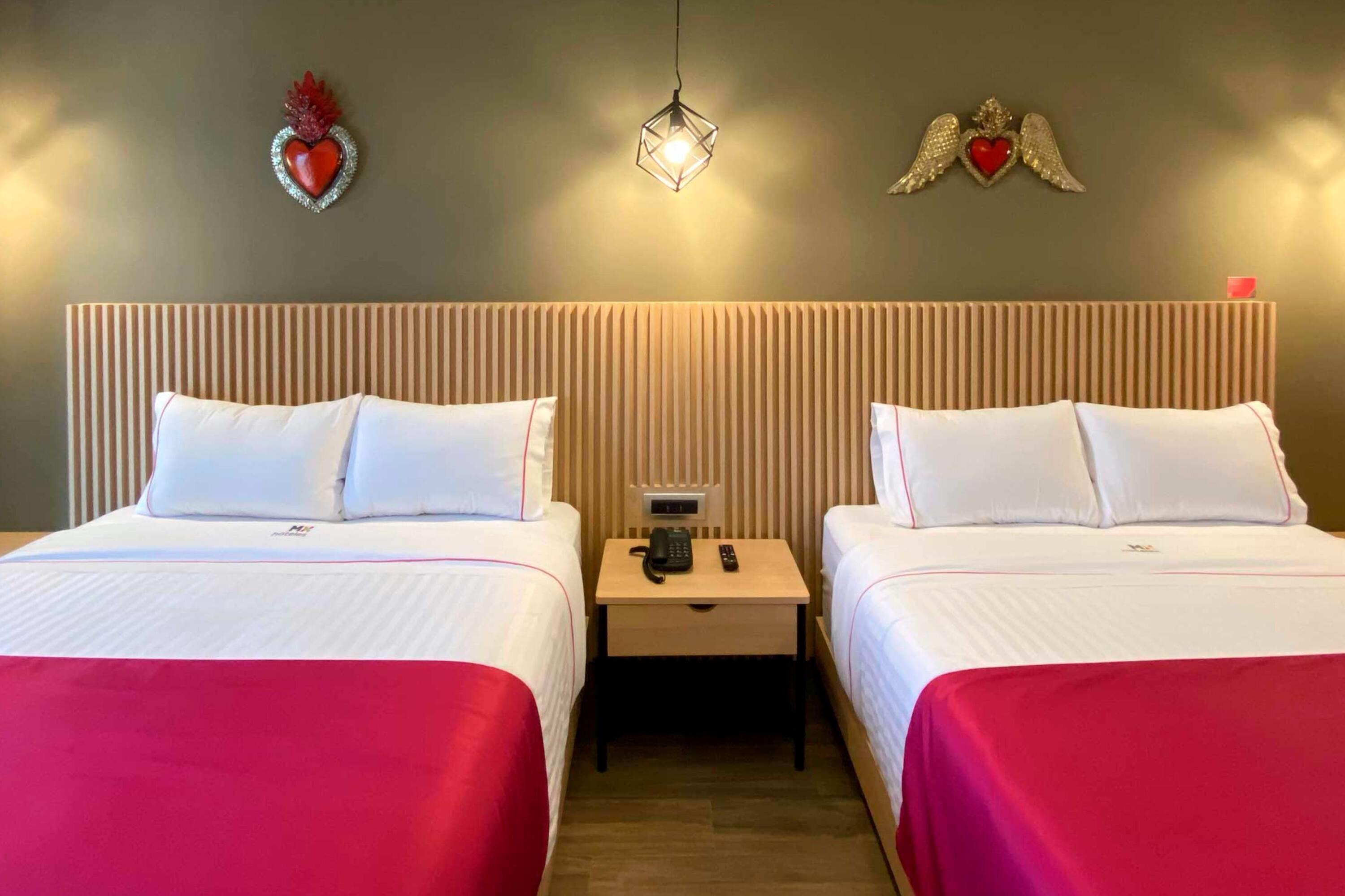 Una habitación de hotel con dos camas, una mesita de noche con teléfono y decoración en la pared.