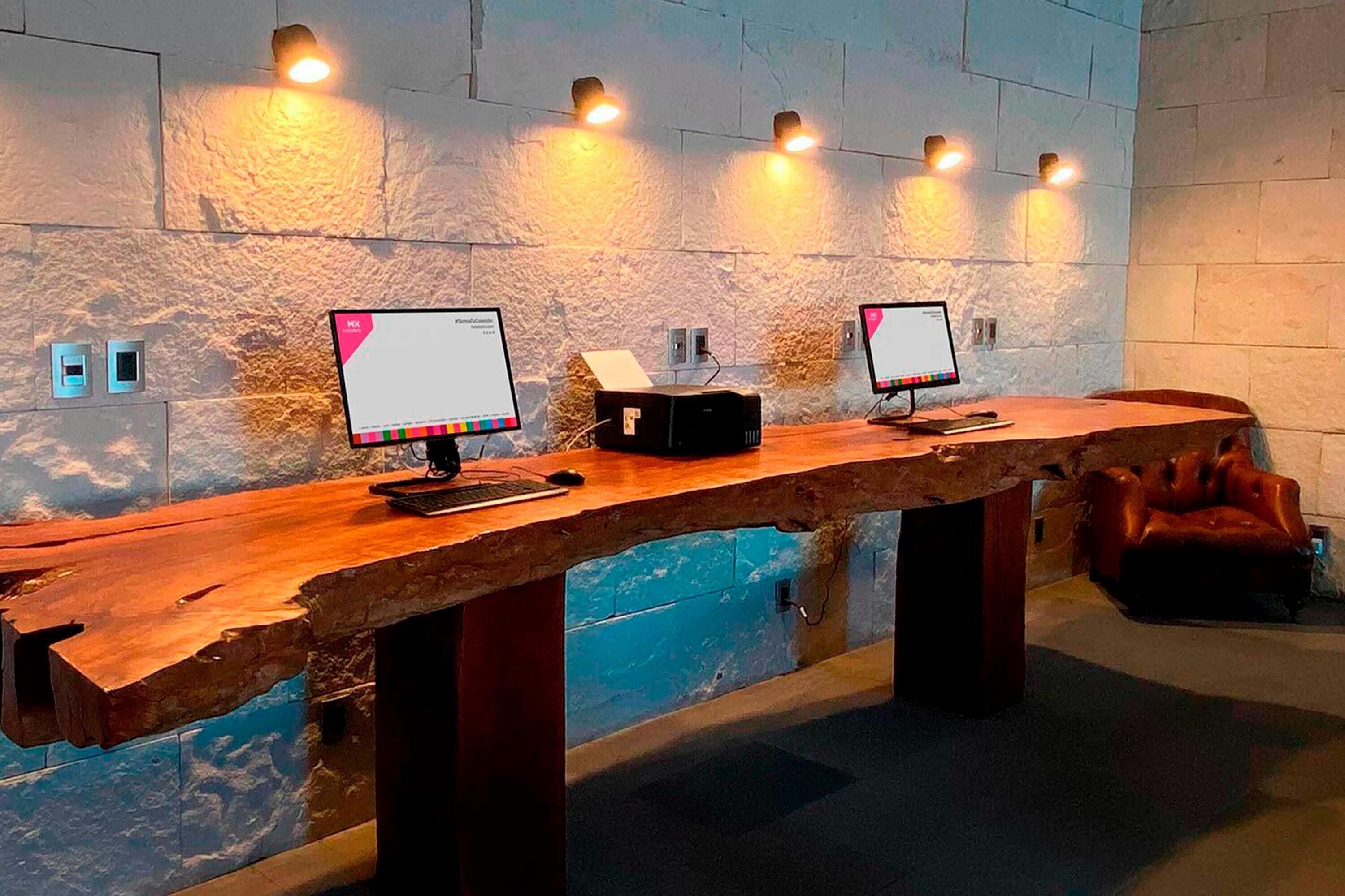 A reception desk with two computer monitors, a telephone, and a black speaker.