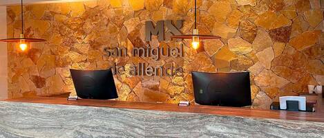 A reception area with a stone wall and two black reception desks.