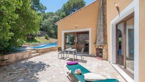 A private villa with a stone patio, outdoor seating, a pool, and a fireplace.