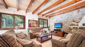 A cozy living room with striped furniture, a television, and a stone wall.