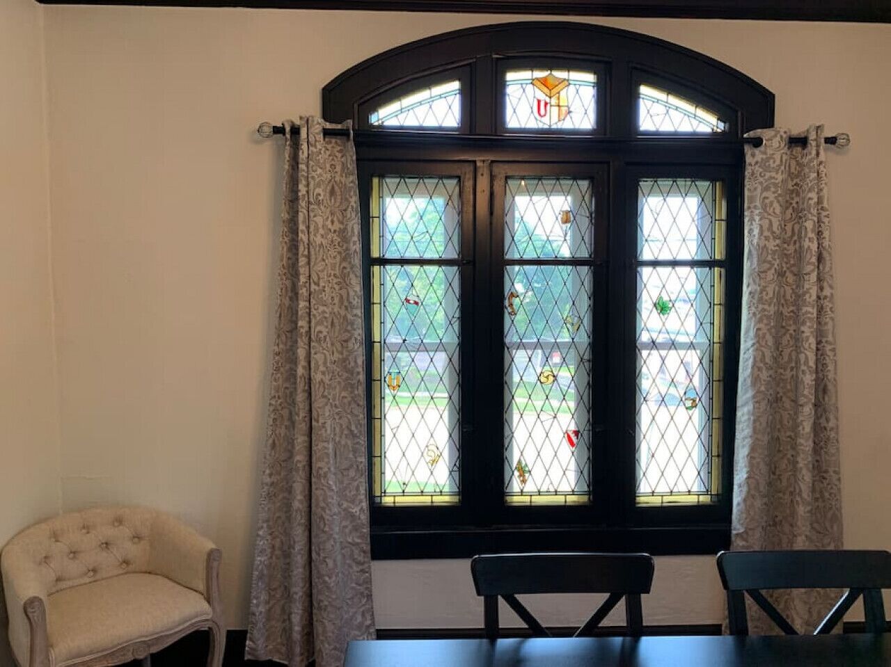 Ein Zimmer mit großem Fenster, einem Sessel und einem Tisch.