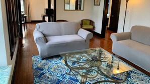 A living room with two sofas, a glass coffee table, and a patterned rug.