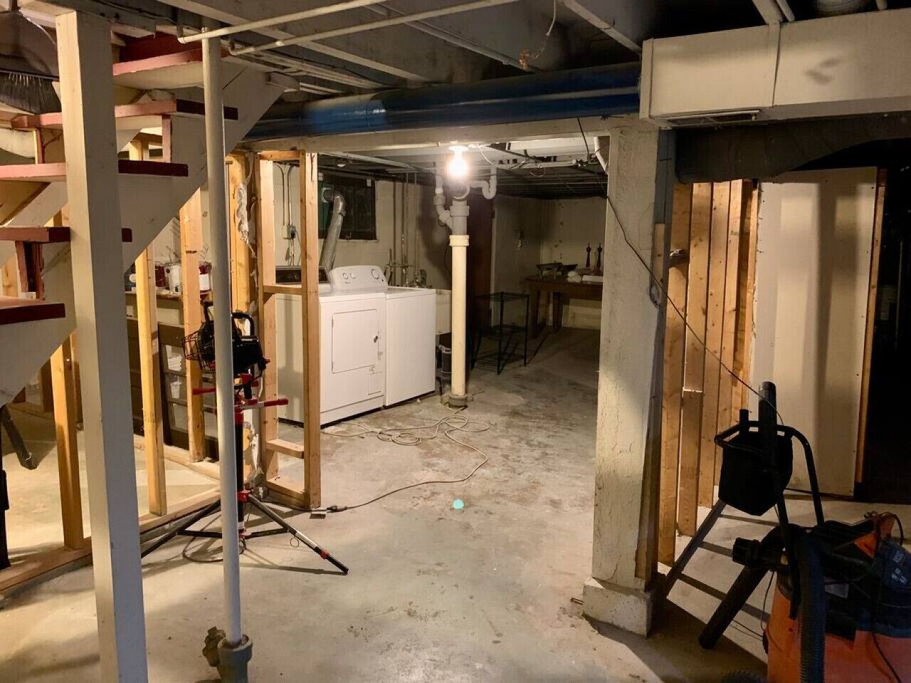 A construction site with exposed wooden beams, a white washing machine, and construction equipment.