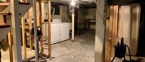 A construction site with exposed wooden beams, a white washing machine, and construction equipment.