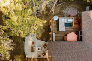 An aerial view of a property with a deck, outdoor seating, a barbecue area, and a pool.