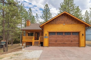 A log cabin with a porch, a garage, and a chimney.