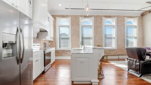A modern kitchen with white cabinetry, a stainless steel refrigerator, and a wooden floor. - Historic downtown apartment with a view (Crowley)