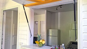 A kitchen with a white countertop, a bowl of fruit, and a tray with drinks and condiments. - Cottage Carambole (Saint-François)