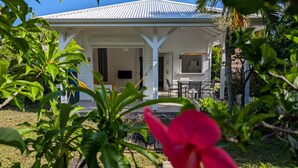 A white house with a covered porch, a dining area, and a small outdoor kitchen. - Cottage Carambole (Saint-François)