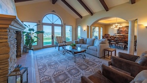 A spacious living room with a fireplace, large windows, and a dining area. - Luxe Ranch with Hot Tub, Gourmet Kitchen and Fabulous Downtown Views. (Paso Robles)