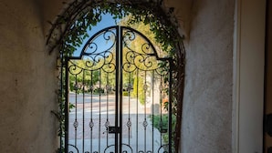 A wrought iron gate with intricate designs, leading to a paved pathway. - Luxe Ranch with Hot Tub, Gourmet Kitchen and Fabulous Downtown Views. (Paso Robles)